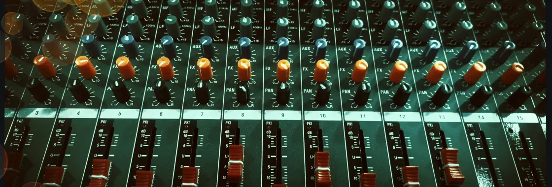 Draufsicht auf ein Mischpult mit roten Schiebereglern und farbigen Drehreglern